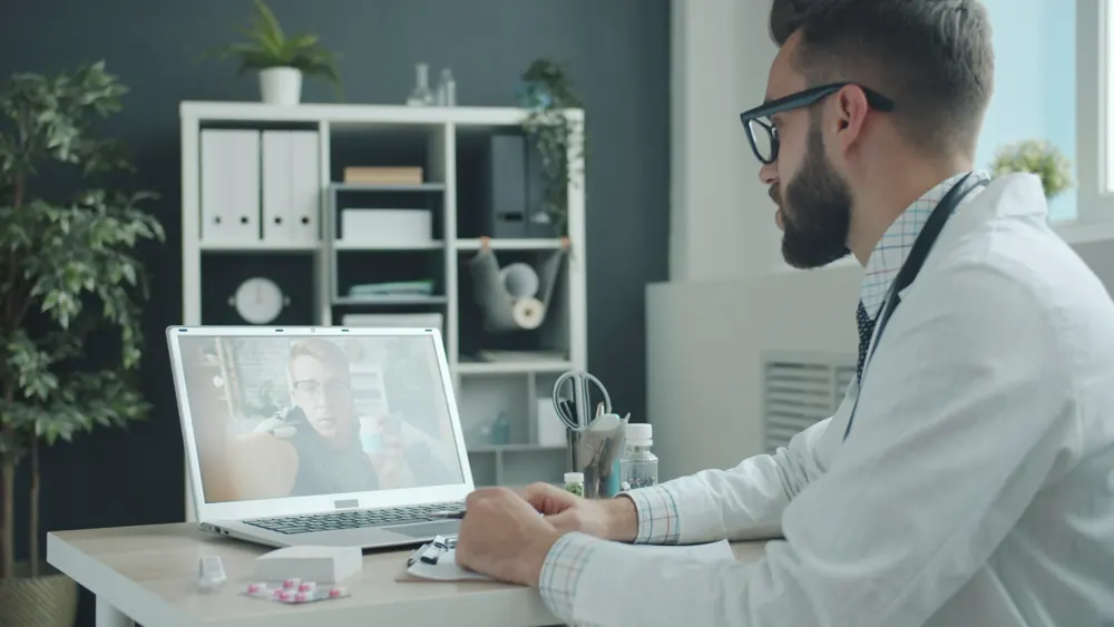 A physician consults a patient by video call from his office